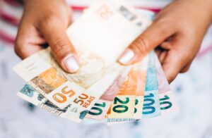 Imagem de mulher segurando várias notas de dinheiro brasileiras