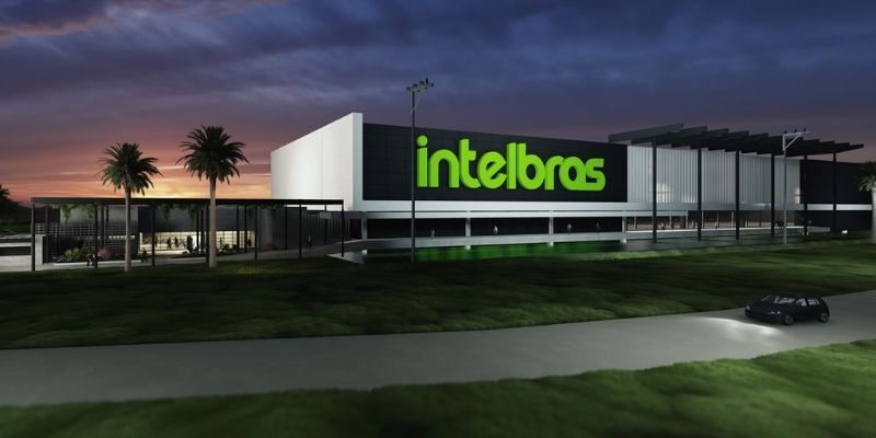 Imagem de projeção digitalizada de fábrica da Intelbras. É possível ver o logo da companhia acima do edifício
