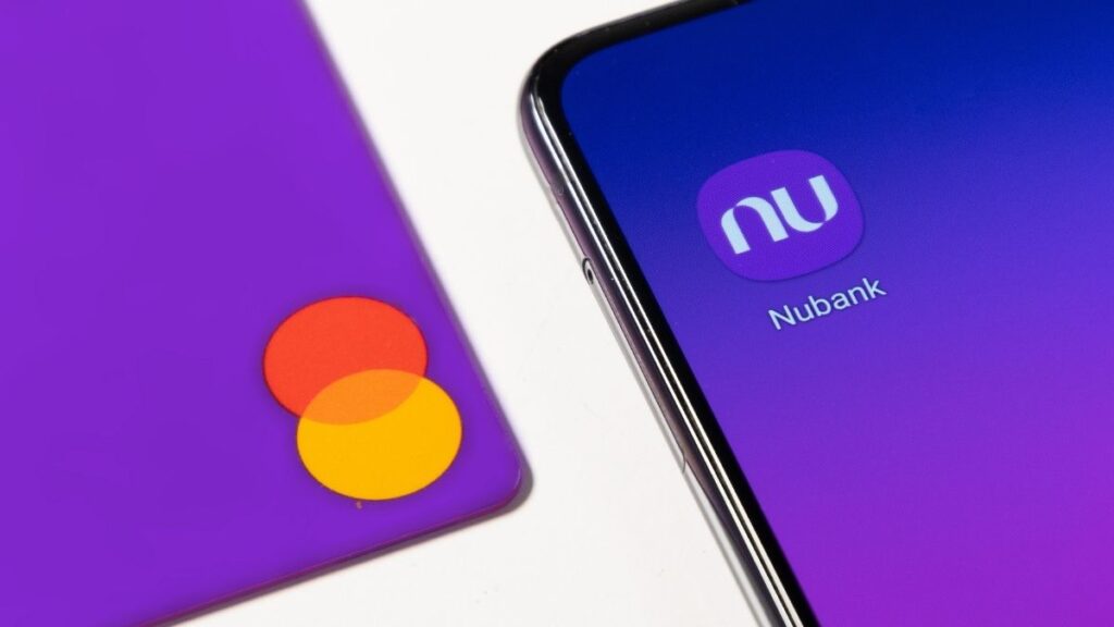 tela de celular estampa símbolo do aplicativo do Nubank ao lado de cartão do roxinho