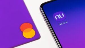 tela de celular estampa símbolo do aplicativo do Nubank ao lado de cartão do roxinho