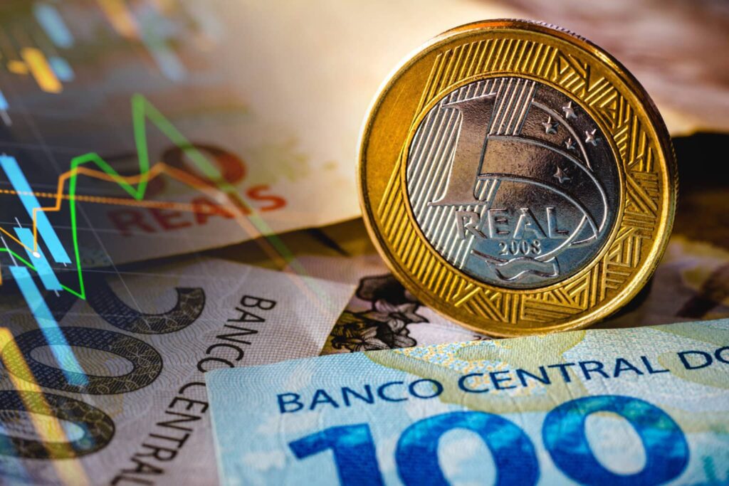 Imagem representando o Banco Central, mostrando moedas e notas de Reais junto a gráficos financeiros.