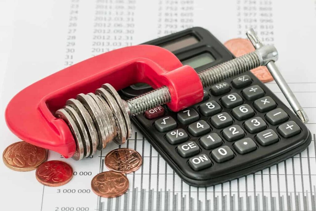 Imagem representando o IOF, mostrando uma calculadora junto a moedas e dados financeiros.