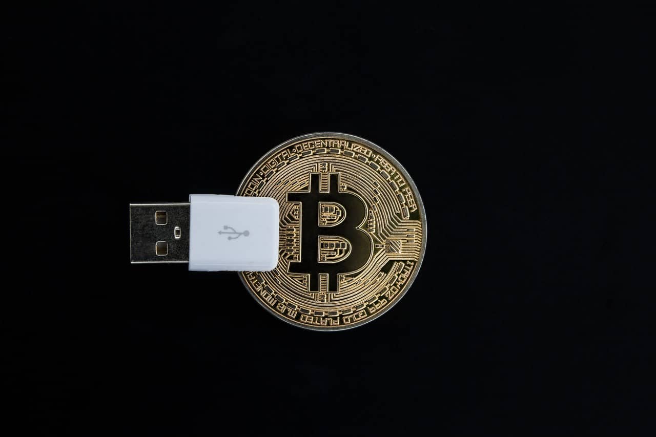 Imagem representando uma wallet, mostrando um pen drive USB junto a uma moeda de bitcoin.