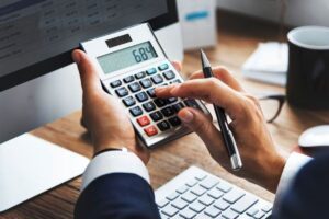 Imagem representando os juros simples, mostrando uma pessoa calculando juros em uma calculadora. mercado